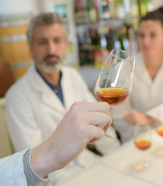 Selerant food and beverage regulatory compliance hand holds wine glass up in room with food scientists