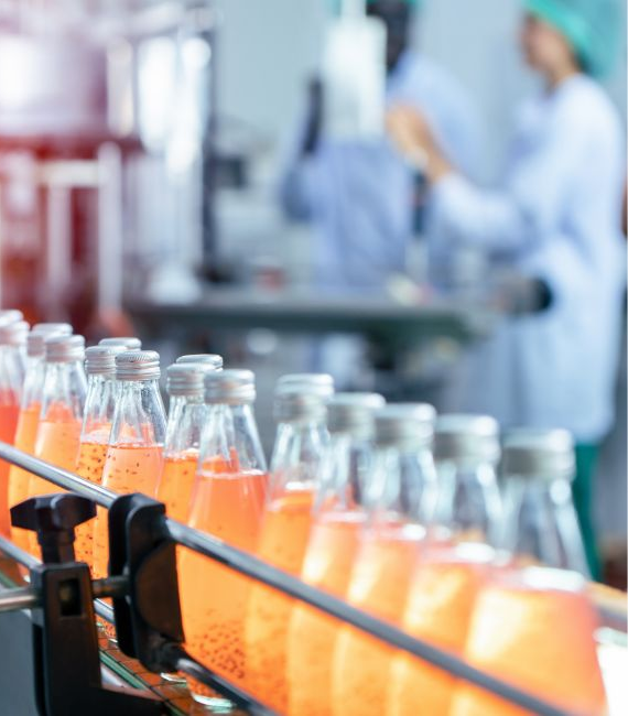 Trace One Devex PLM orange beverage bottles on a conveyor belt in manufacturing plant